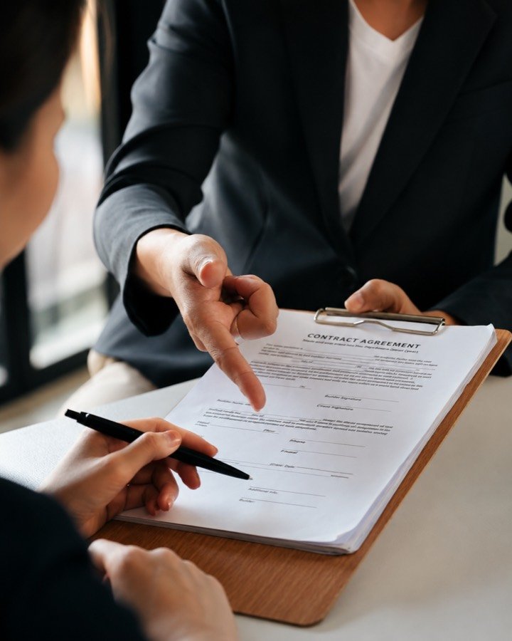 Asesora señalando una cláusula de un contrato sobre la mesa