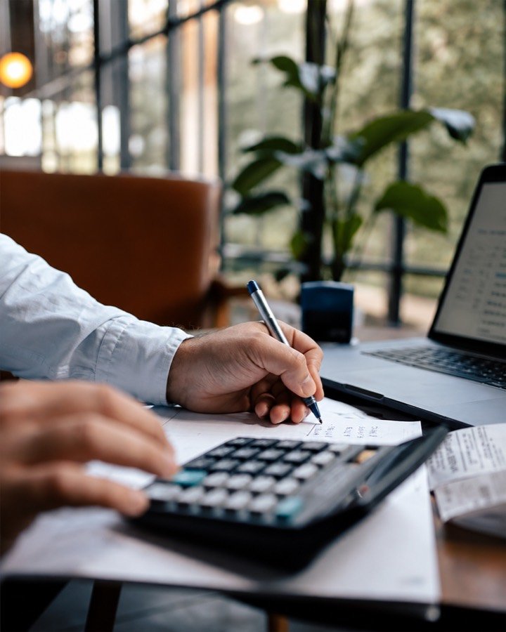 Escritorio con calculadora, comprobantes y laptop durante una revisión contable